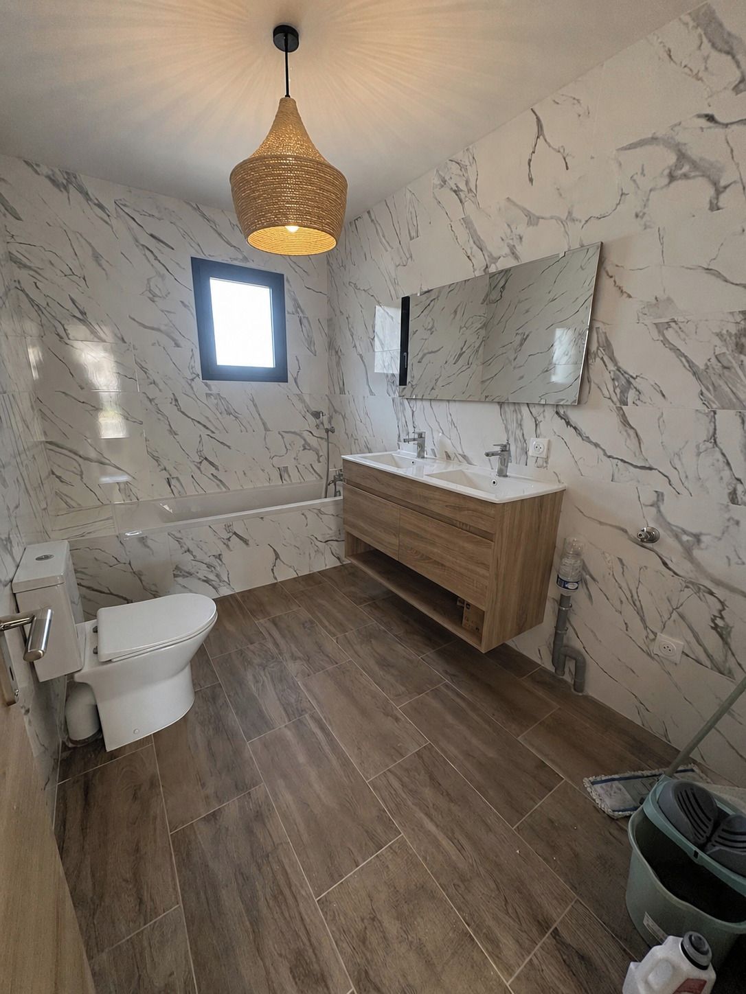 A bathroom with a toilet, sink, vanity, and a large mirror.