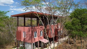 Um edifício vermelho de dois andares com um alpendre coberto, rodeado por árvores.