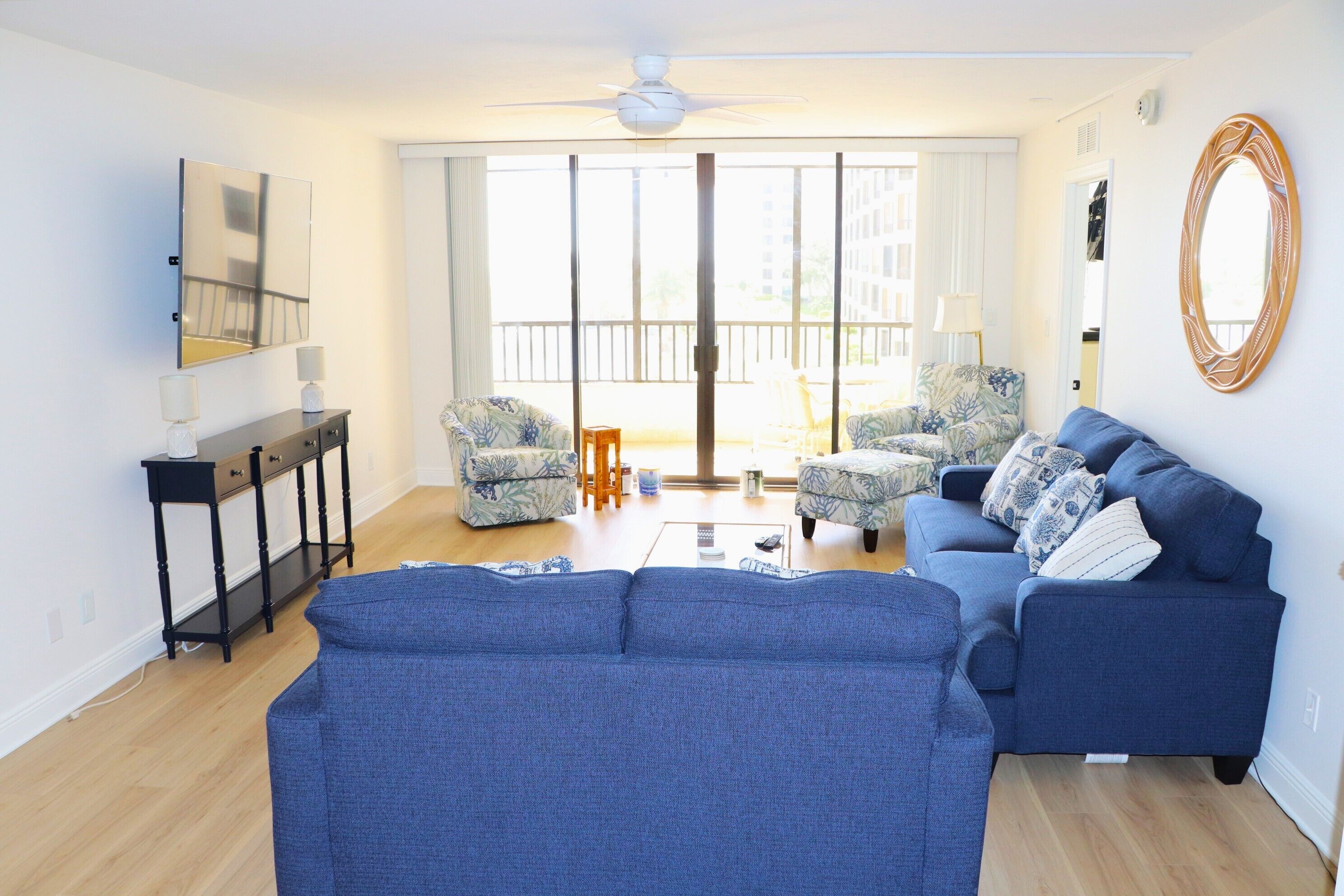 A living room with a blue sofa, two patterned armchairs, a small coffee table, and a ceiling fan.
