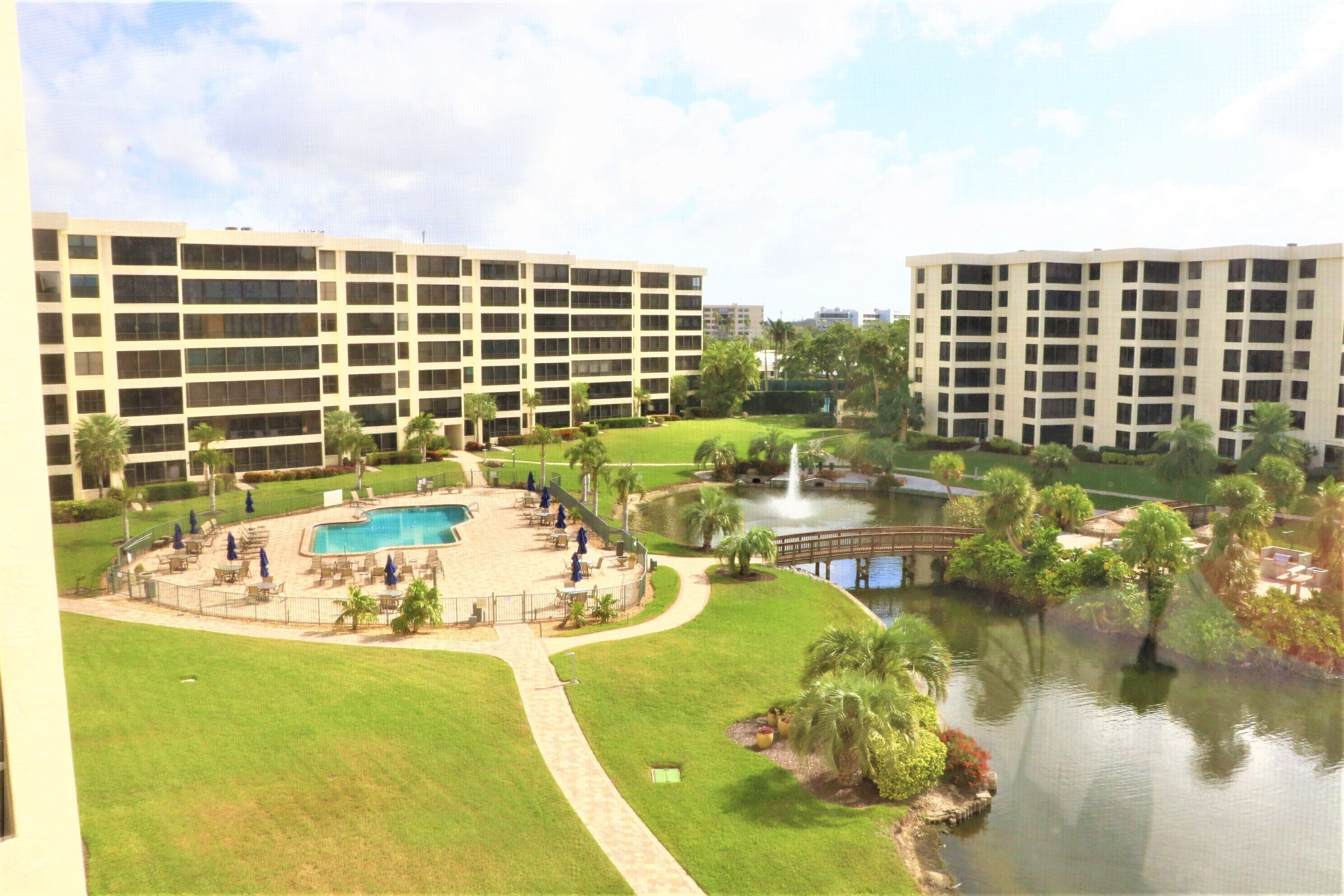 A hotel with multiple buildings, a swimming pool, and a small pond with a bridge.