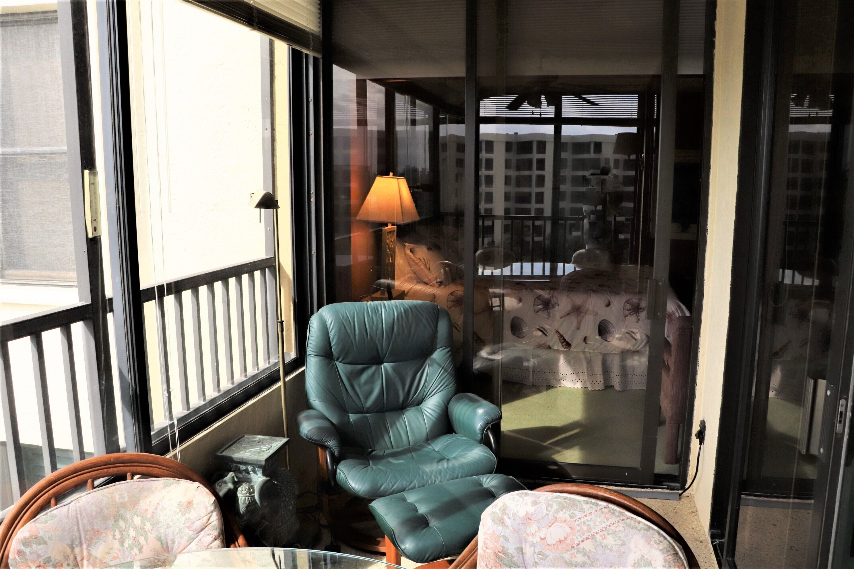 A balcony with a green leather chair, a small table, and a lamp.