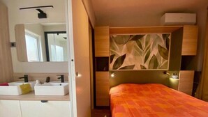 A bedroom with a bed, bedside table, and a mirror. - Chalet in a 5-star resort with swimming pools (Puget-sur-Argens)