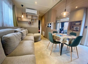 Ein modernes Wohnzimmer mit einer Couch, einem Esstisch, Stühlen und Einbauschränken.