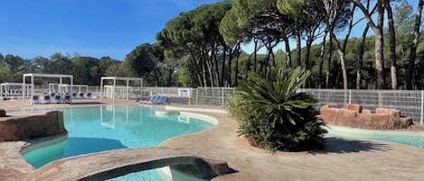 A swimming pool with clear water, surrounded by trees and a white fence.