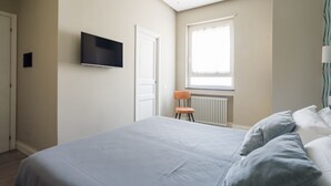 A bedroom with a bed, a television mounted on the wall, a window, and a radiator. - Weaver Suite 5 By Dimorra  (Naples)