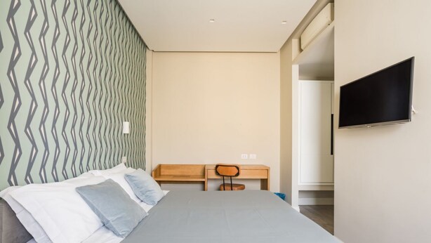 A hotel room with a bed, a desk, a chair, and a television. - Weaver Suite 5 By Dimorra  (Naples)