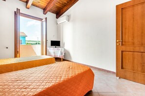 A bedroom with a bed, a television, and a door leading to an outdoor area.