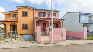 A two-story building with a pink and yellow facade, a visible staircase, and a clear sky. - GuestHost - Sweet Home in Portoscuso! (Portoscuso)