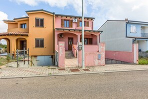 A two-story building with a pink and yellow facade, a visible staircase, and a clear sky. - GuestHost - Sweet Home in Portoscuso! (Portoscuso)