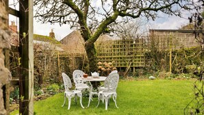 A garden with a table and chairs, a tree, and a stone wall. - Grand Devon Country House for 15 (Leyburn)