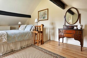 Ein Schlafzimmer mit einem Bett, Nachttischlampen, einem Schminktisch mit Spiegel und einem Bild an der Wand.