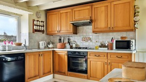 A kitchen with wooden cabinets, a stove, an oven, a microwave, and a dishwasher. - Grand Devon Country House for 15 (Leyburn)