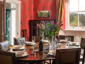 A dining table set for six with plates, glasses, and a bottle. - Georgian Devon House With Hot Tub (Ilfracombe)