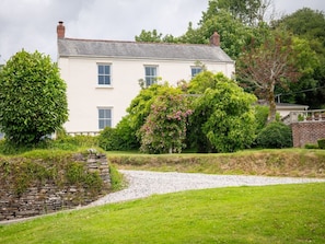 A two-story house with a white exterior, a gravel driveway, and a stone wall. - Georgian Devon House With Hot Tub (Ilfracombe)