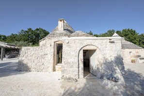 Ein Steinhaus mit Schornstein, offener Tür und kleiner Veranda.