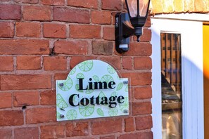 Eine Ziegelmauer mit einem Schild, auf dem 'Lime Cottage' steht.