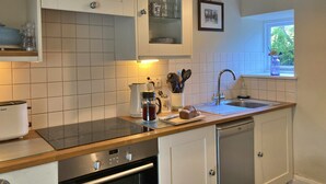 A modern kitchen with white cabinets, a Bosch dishwasher, and a window with a view of greenery. - Charming Snowdonia Cottage for 4 (Betws-Y-Coed)