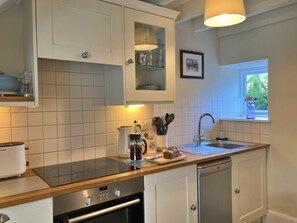 A modern kitchen with white cabinets, a Bosch dishwasher, and a window with a view of greenery. - Charming Snowdonia Cottage for 4 (Betws-Y-Coed)