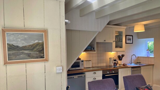 A kitchen with white cabinets, a microwave, a coffee maker, and a window. - Charming Snowdonia Cottage for 4 (Betws-Y-Coed)