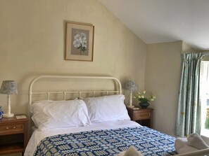 A bedroom with a bed, two bedside tables, a lamp, a framed picture on the wall, and a window with curtains. - Charming Snowdonia Cottage for 4 (Betws-Y-Coed)