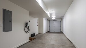 Ein sauberer, leerer Flur mit weißen Wänden, einem Betonboden und einer geschlossenen Garagentür am Ende.