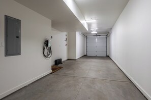 Een schone, lege gang met witte muren, een betonnen vloer en een gesloten garagedeur aan het einde.