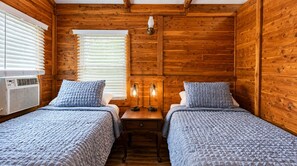 Een kamer in chaletstijl met twee bedden, houten wanden, een houten tafel en een wandlamp.