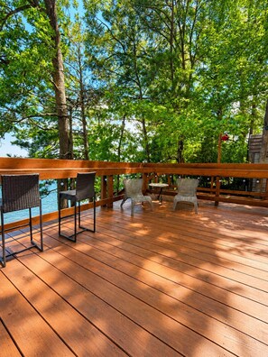 Een houten terras met rieten stoelen en een tafel, met uitzicht op een waterpartij.