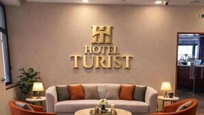 En hotellobby med en soffa, två fåtöljer, ett soffbord och en receptionsdisk.