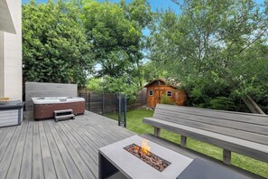 A deck with a fire pit, a hot tub, and a wooden bench. - Hot tub and fire pit deck near downtown (Austin)