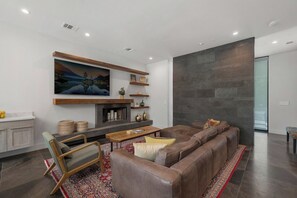 Ein modernes Wohnzimmer mit einer großzügigen Eckcouch, einem Kamin und einem großen Gemälde an der Wand.