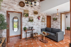 A living room with a brick wall, a gray sofa, a glass coffee table, and a sewing machine.