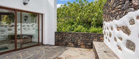A modern building with a stone patio, a glass door entrance, and a stone wall with a unique texture.