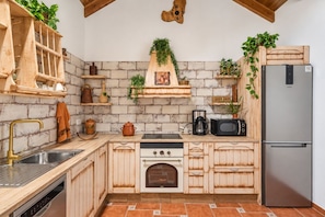 Una cocina con armarios de madera, un lavamanos de acero inoxidable, un horno empotrado y un refrigerador.