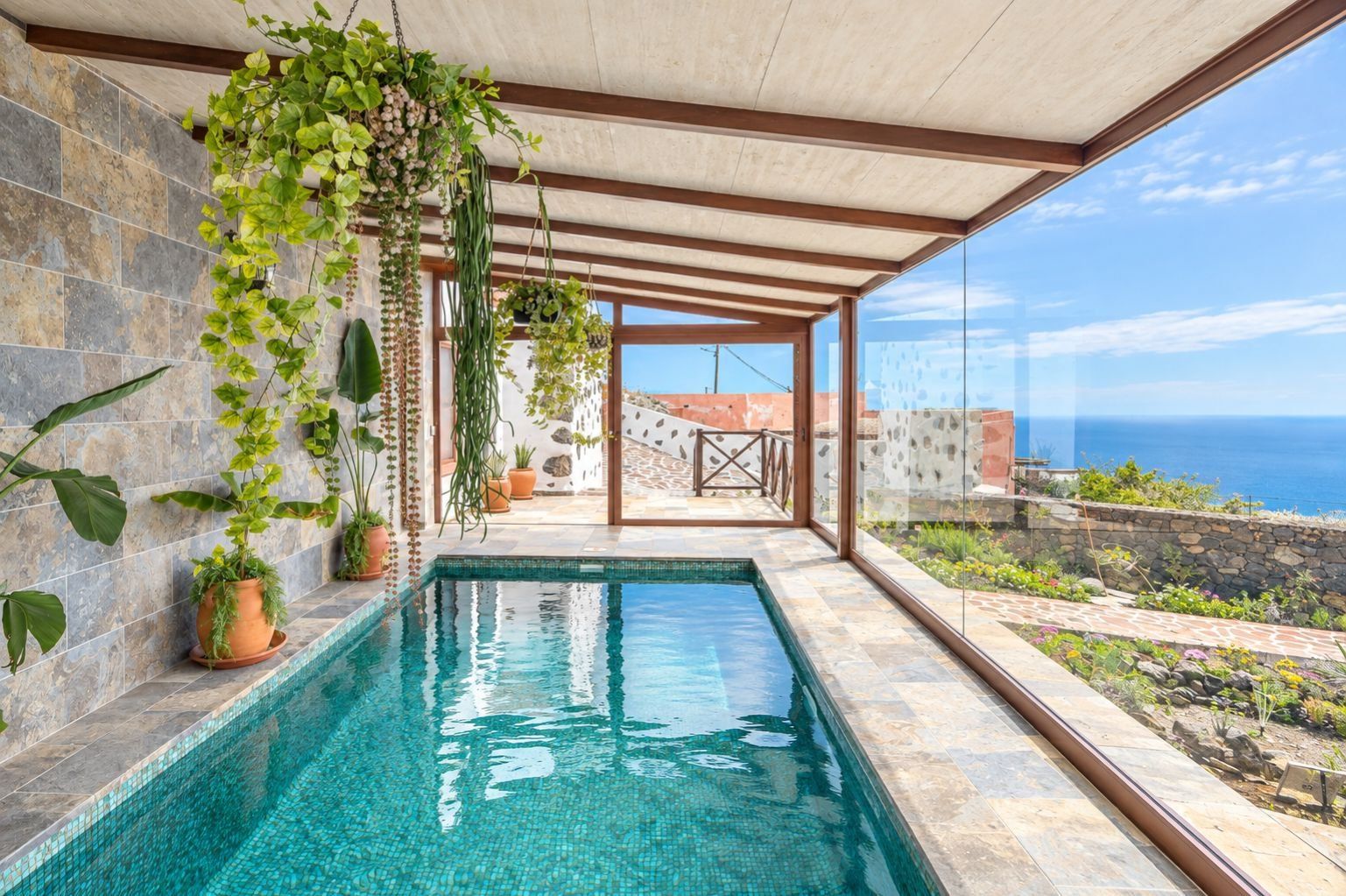 An indoor swimming pool with a clear view of the sea through large windows.