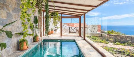 An indoor swimming pool with a clear view of the sea through large windows.