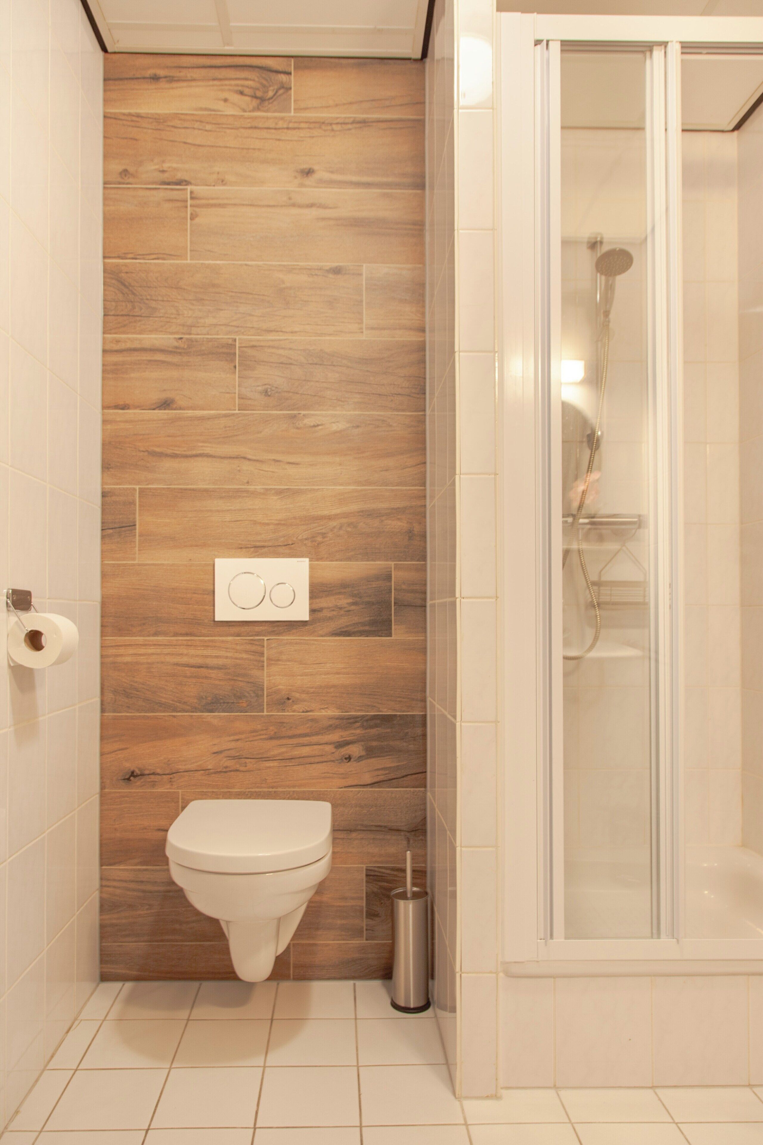 Un bagno con un WC, una doccia e un rivestimento in legno.