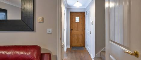 A hallway with a wooden door, a red leather sofa, and a ceiling light fixture.