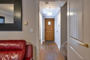 A hallway with a wooden door, a red leather sofa, and a ceiling light fixture.