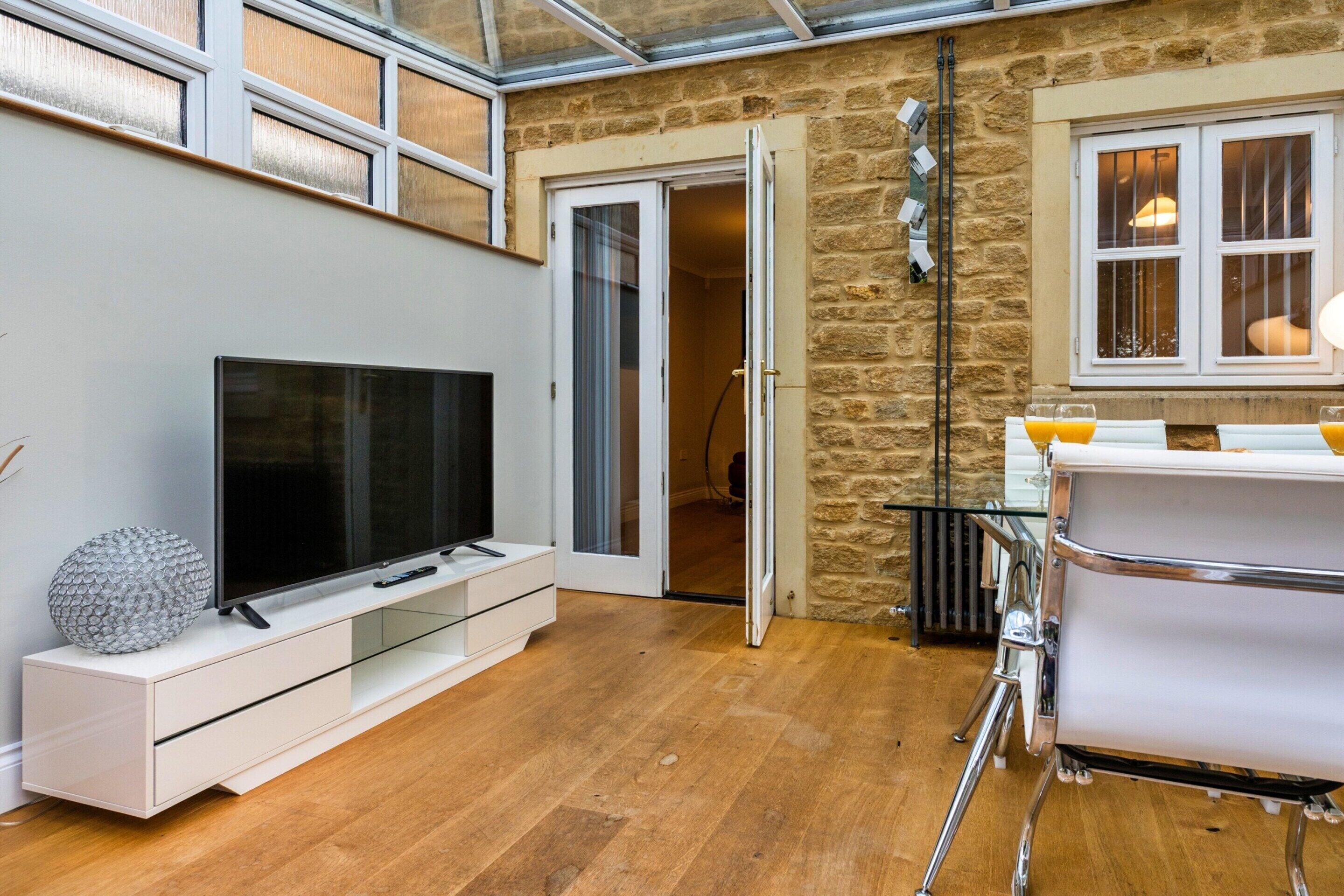 Una sala de estar moderna con un televisor de pantalla plana, una mesa de centro de vidrio y una pared de piedra.