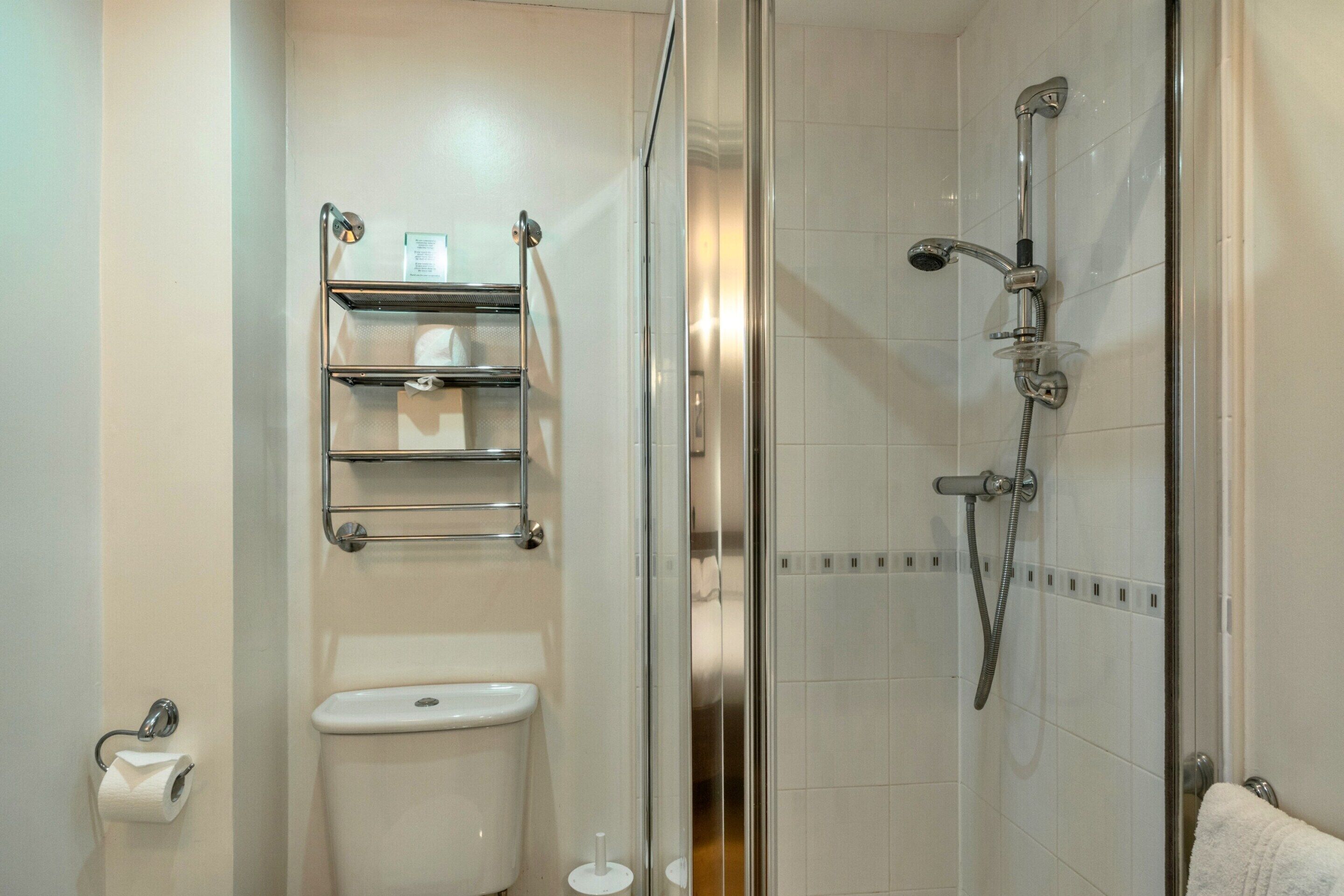 A bathroom with a toilet, a glass shower enclosure, and a towel rack.