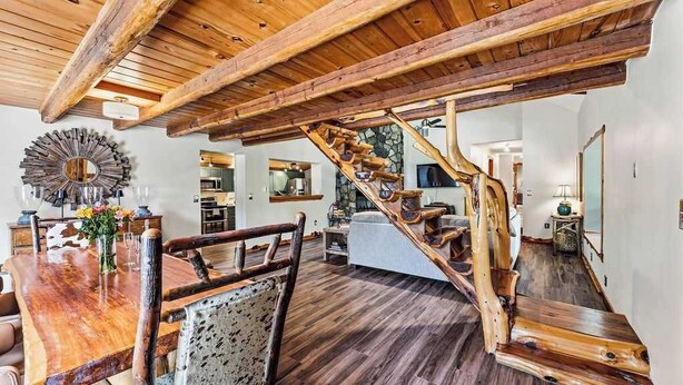 Ein geräumiger Wohnbereich mit einer Holztreppe, einem Esstisch mit Stühlen und einem großen Spiegel.