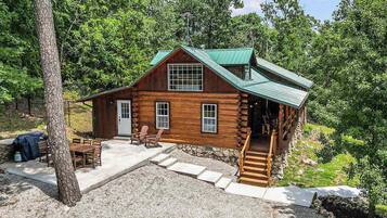 A log cabin with a porch, a dining area, and a staircase leading to the upper level.