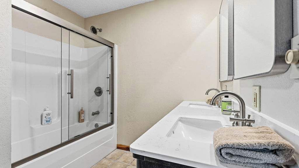 Une salle de bain avec une douche à parois de verre, un lavabo blanc avec une serviette et un miroir.