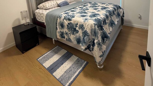 Una camera da letto con un letto, un comodino e un quadro appeso al muro.