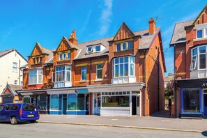 A row of red brick buildings with a storefront on the ground floor. - The St Annes Beach Collection (Lytham St Annes)