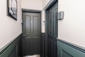 A hallway with a dark wooden door, a doorbell, and a framed picture on the wall. - The St Annes Beach Collection (Lytham St Annes)