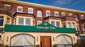 A hotel named 'Emerald Tide' with a green awning, a wooden front door, and large windows with curtains. - Emerald Tide Hotel (Blackpool)