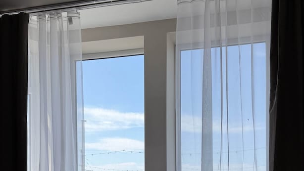 A hotel room with a large window, a bed, and a view of the beach. - Emerald Tide Hotel (Blackpool)