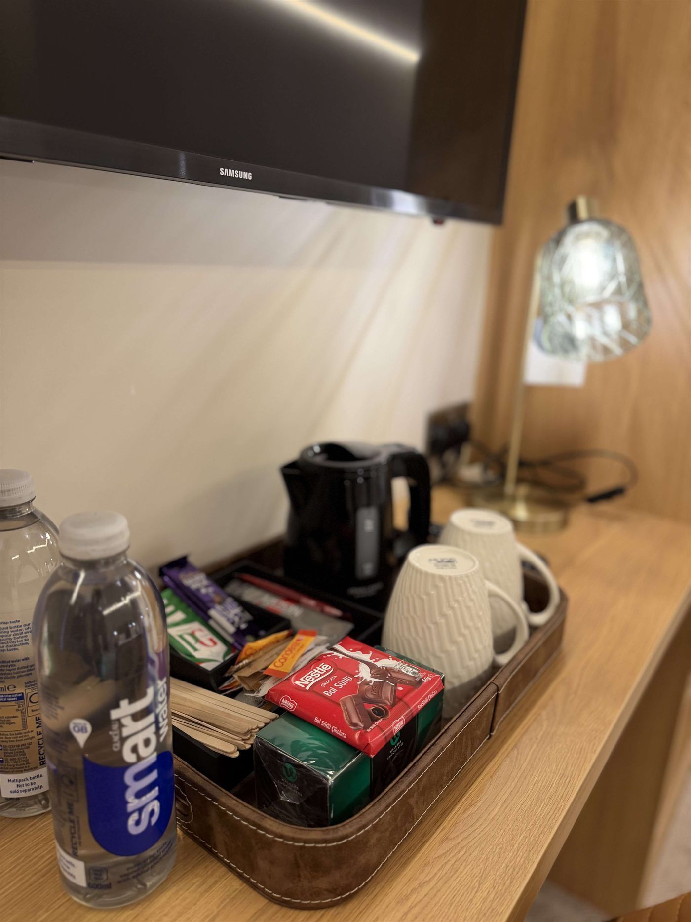 Un espacio con kitchenette equipado con microondas, hervidor de agua, cafetera y una bandeja con snacks y una botella de agua.
